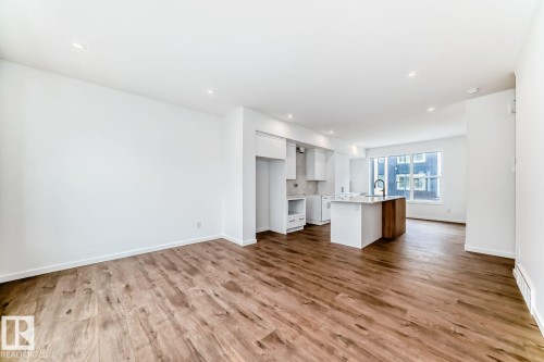 Open-concept living area with wood-finish flooring, white walls, and recessed lighting - #67 5 Rondeau Dr, St. Albert, AB - Indoor