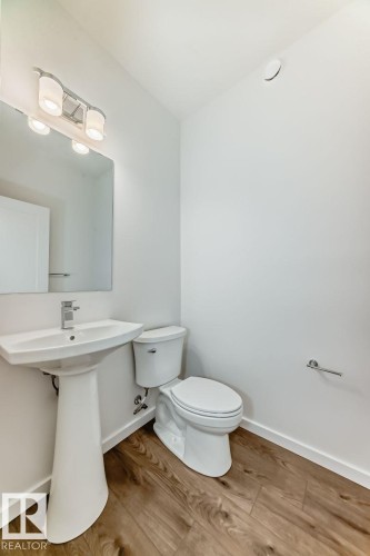 Powder room featuring a pedestal sink with chrome faucet, a rectangular wall-mounted mirror, and a contemporary vanity light fixture - #67 5 Rondeau Dr, St. Albert, AB - Indoor Photo Showing Bathroom