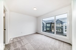 Spacious interior with neutral-toned carpeting, white walls, and a large window offering ample natural light - 