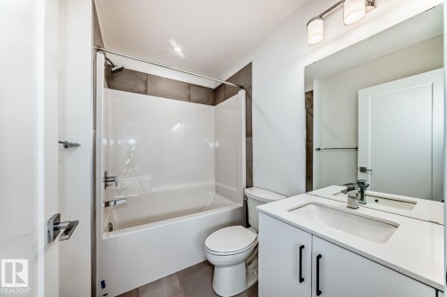 Contemporary bathroom featuring a white vanity with a rectangular sink, chrome faucet, and black cabinet hardware - #67 5 Rondeau Dr, St. Albert, AB - Indoor Photo Showing Bathroom