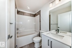 Contemporary bathroom featuring a white vanity with a rectangular sink, chrome faucet, and black cabinet hardware - 