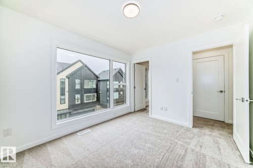 Room featuring a large picture window, neutral wall paint, and light-toned carpeting - #67 5 Rondeau Dr, St. Albert, AB - Indoor Photo Showing Other Room
