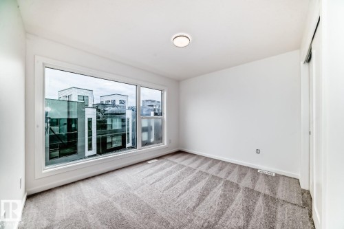 Large picture window with white trim, gray patterned carpeting, white walls, and a ceiling-mounted light fixture - #67 5 Rondeau Dr, St. Albert, AB - Indoor Photo Showing Other Room