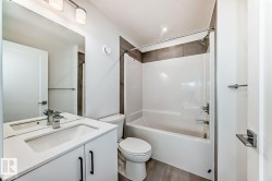 Bathroom featuring a modern vanity with integrated sink, white cabinetry, and matte black hardware - 