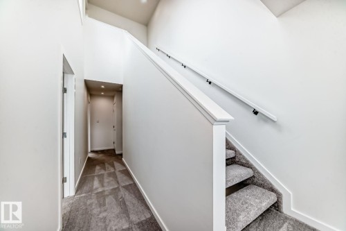 Staircase with white railing, black metal handrails, and gray patterned carpet - #67 5 Rondeau Dr, St. Albert, AB - Indoor Photo Showing Other Room