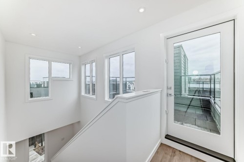 Upper-level landing featuring a full-glass door providing access to an outdoor terrace with glass railings - #67 5 Rondeau Dr, St. Albert, AB - Indoor Photo Showing Other Room