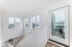 Upper-level landing featuring a full-glass door providing access to an outdoor terrace with glass railings - 