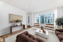 Bright living area featuring large windows with white roller blinds, wood-finish flooring, and white walls - 