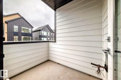 Outdoor balcony featuring horizontal panel siding, a concrete floor, and a black-capped half-wall - 