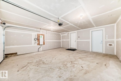 Spacious garage featuring a concrete floor, two white entry doors, and exposed drywall - #67 5 Rondeau Dr, St. Albert, AB - Indoor Photo Showing Garage