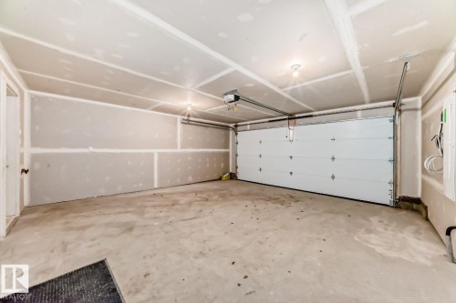 Spacious garage with concrete flooring, prepped drywall, and an overhead garage door - #67 5 Rondeau Dr, St. Albert, AB - Indoor Photo Showing Garage
