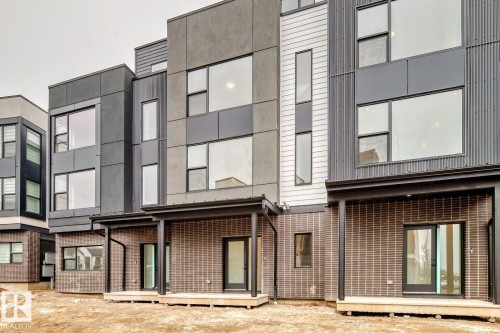 Modern townhome exterior featuring multi-level architecture, large picture windows, and a mix of dark gray siding with vertical corrugated metal accents - #67 5 Rondeau Dr, St. Albert, AB - Outdoor