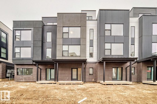 Contemporary townhome exterior featuring multi-textured siding, large windows, covered patios, and sliding glass doors - #67 5 Rondeau Dr, St. Albert, AB - 
