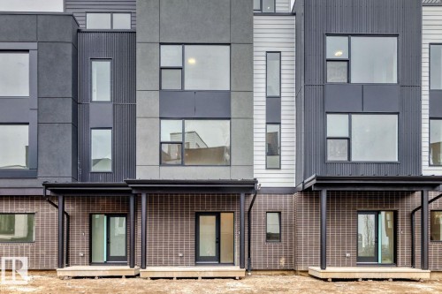 Modern townhouse exteriors featuring a combination of gray and white horizontal siding, corrugated metal accents, and brick facades - #67 5 Rondeau Dr, St. Albert, AB - 