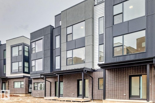 Modern multi-story facade featuring dark grey paneling, vertical corrugated siding, and large windows - #67 5 Rondeau Dr, St. Albert, AB - Outdoor