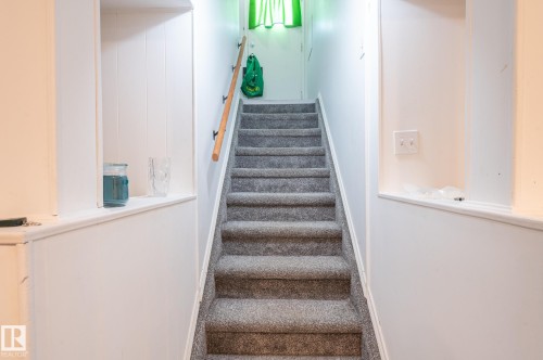 Staircase featuring grey carpeted treads, a natural wood handrail, and white paneled walls - 13816 62 Street, Edmonton, AB 
