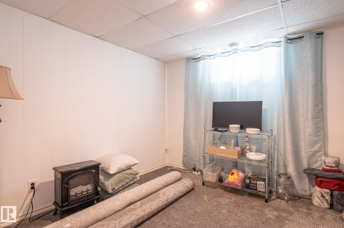 Carpeted room featuring white panel walls and a drop ceiling - 13816 62 Street, Edmonton, AB 