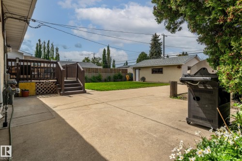 Expansive concrete patio with a tiered wood deck featuring railings and lattice detailing - 13816 62 Street, Edmonton, AB 