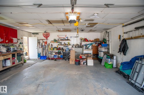 Spacious garage with concrete flooring, multiple ceiling fans, and a built-in workbench - 13816 62 Street, Edmonton, AB 