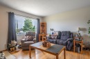 Bright living area featuring a large picture window, wood-finish flooring, a neutral wall color - 13816 62 Street, Edmonton, AB 