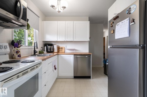 Kitchen featuring white cabinetry, wood-finish countertops, and a white tile backsplash - 13816 62 Street, Edmonton, AB 