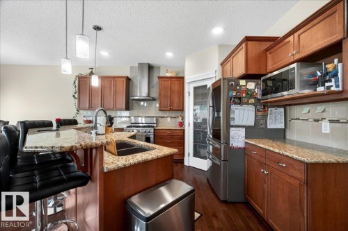 Kitchen featuring wood-finish cabinetry, granite countertops, stainless steel appliances, and a central island with pendant lighting - 1411 30 Avenue, Edmonton, AB 