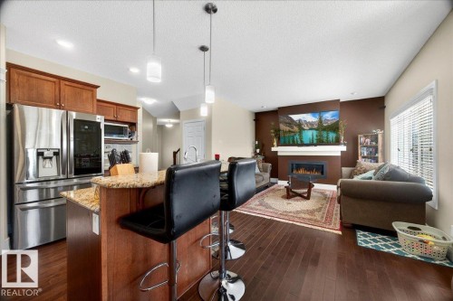 Open-concept living area featuring rich wood-finish flooring, a contemporary fireplace with a white mantel, and recessed lighting - 1411 30 Avenue, Edmonton, AB 