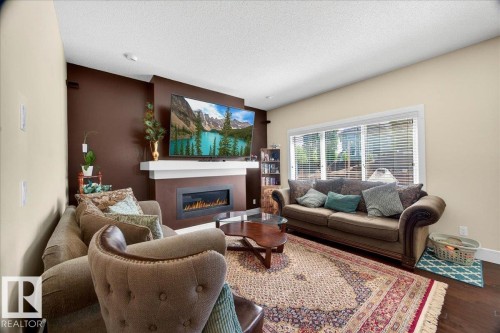 Living area featuring a contemporary electric fireplace with a white mantel, dark accent wall, and recessed lighting - 1411 30 Avenue, Edmonton, AB 