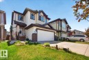 Two-story property featuring light-toned siding, dark trim, an attached double garage, and a concrete driveway - 1411 30 Avenue, Edmonton, AB 