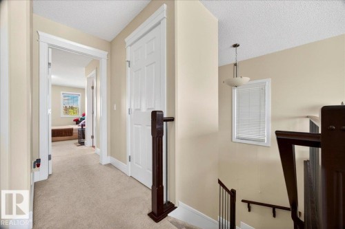 Upper-level hallway featuring a neutral color palette, paneled interior doors, light-toned carpeting, and white trim throughout - 1411 30 Avenue, Edmonton, AB 