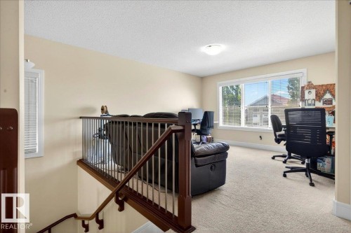 Carpeted upper-level landing with a wood and metal railing overlooking the staircase - 1411 30 Avenue, Edmonton, AB 