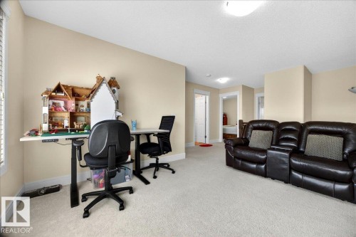 Spacious carpeted room with neutral wall tones and a sloped ceiling - 1411 30 Avenue, Edmonton, AB 