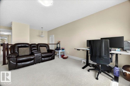 Carpeted upper-level bonus room with neutral wall tones, white baseboards, and a semi-flush ceiling light fixture - 1411 30 Avenue, Edmonton, AB 