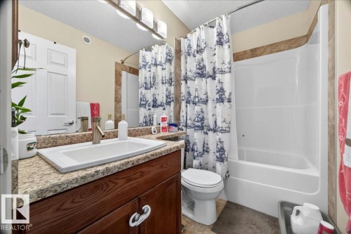 Bathroom featuring a built-in vanity with a granite-style countertop, undermount sink, and wood-finish cabinetry - 1411 30 Avenue, Edmonton, AB 