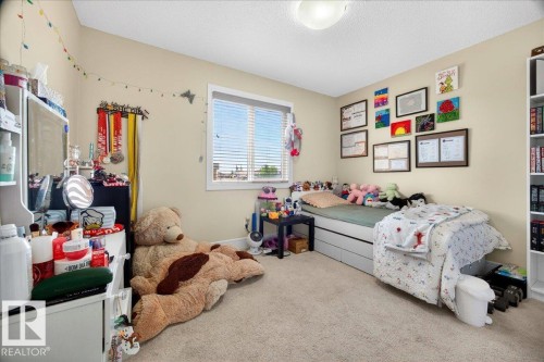 Carpeted room featuring a white-framed window with blinds, a built-in white bookshelf, and a flush-mount ceiling light - 1411 30 Avenue, Edmonton, AB 