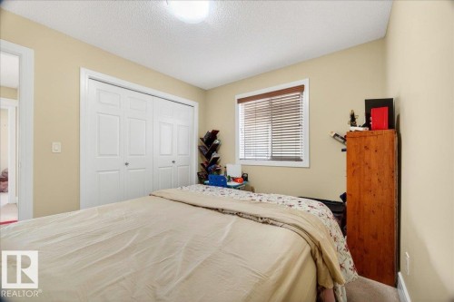 Bedroom featuring an expansive closet with bi-fold doors, a single window with blinds, and neutral-toned walls - 1411 30 Avenue, Edmonton, AB 