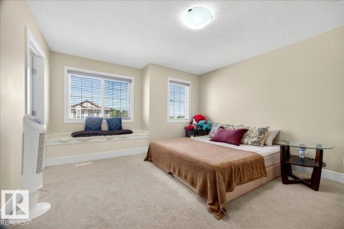 Neutral-toned bedroom featuring a built-in window seat, two windows with horizontal blinds, and neutral carpet flooring - 1411 30 Avenue, Edmonton, AB 