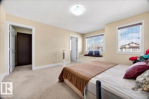Bedroom featuring neutral carpet flooring, recessed window seats, two large windows with horizontal blinds, and a flush mount ceiling light - 1411 30 Avenue, Edmonton, AB 