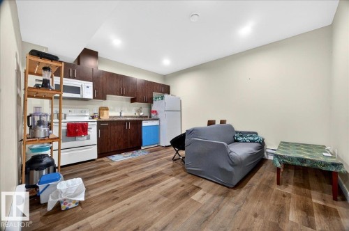 Open-concept living area with wood-finish flooring, recessed lighting, and a full kitchen - 1411 30 Avenue, Edmonton, AB 