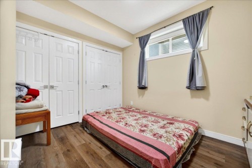 Room featuring wood-finish flooring, a window with horizontal blinds, and two sets of bi-fold closet doors - 1411 30 Avenue, Edmonton, AB 