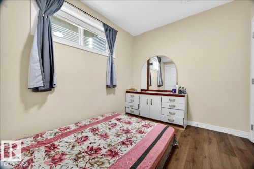 Interior space with wood-finish flooring, a white trim baseboard, and a window featuring horizontal blinds - 1411 30 Avenue, Edmonton, AB 
