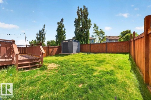 Expansive backyard featuring a wood deck with steps, a manicured lawn, a storage shed, and a privacy fence - 1411 30 Avenue, Edmonton, AB 
