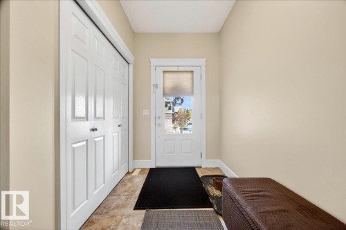 Entryway featuring a paneled glass-insert door, tile flooring, and bi-fold closet doors with white trim - 1411 30 Avenue, Edmonton, AB 