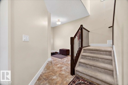 Staircase featuring carpeted treads, dark wood newel posts, and balusters - 1411 30 Avenue, Edmonton, AB 