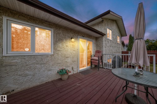 Expansive wood-finish deck with white railing, featuring sliding glass door access to the interior - 3843 47 Street, Edmonton, AB 