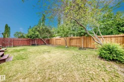 Expansive fenced backyard featuring a combination of red-stained and natural wood fencing - 