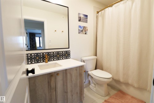 Main bathroom featuring a vanity with a white countertop, patterned tile backsplash, and a wood-finish cabinet - 100 Graybriar Drive, Stony Plain, AB - Indoor Photo Showing Bathroom