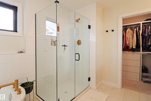 Glass-enclosed shower with subway tile surround, an integrated shower niche, and brass-finish hardware. - 100 Graybriar Drive, Stony Plain, AB - Indoor