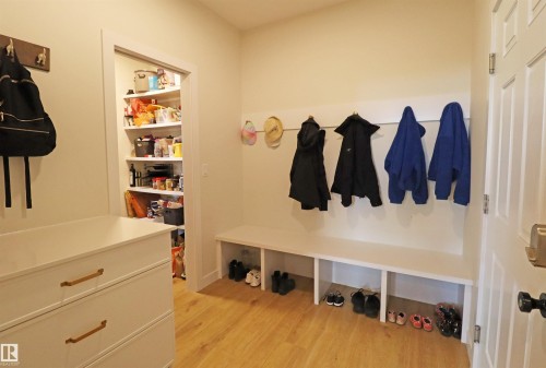 Mudroom area featuring a built-in bench with shoe storage, wall-mounted coat hooks, and built in storage cabinet with quartz top. - 100 Graybriar Drive, Stony Plain, AB - Indoor