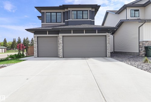 Contemporary exterior featuring a finished and heated three-car garage with stone accents, and dark trim - 100 Graybriar Drive, Stony Plain, AB - Outdoor